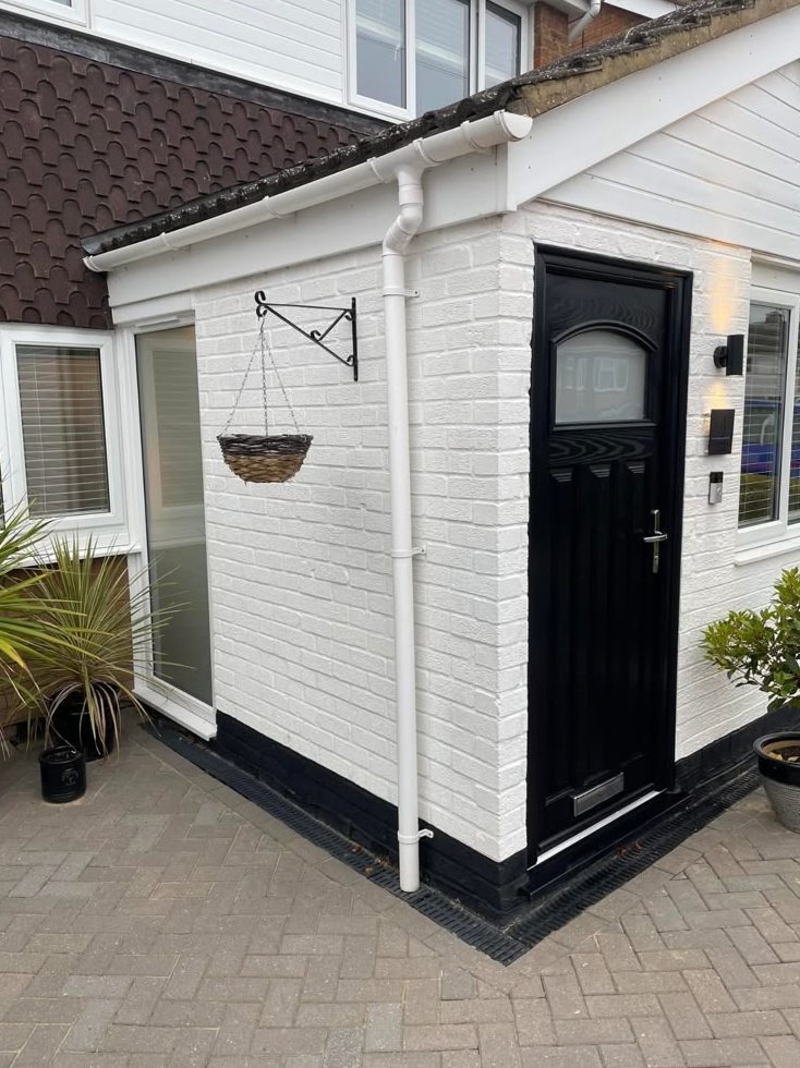 Black entrance door on a white-painted brick porch
